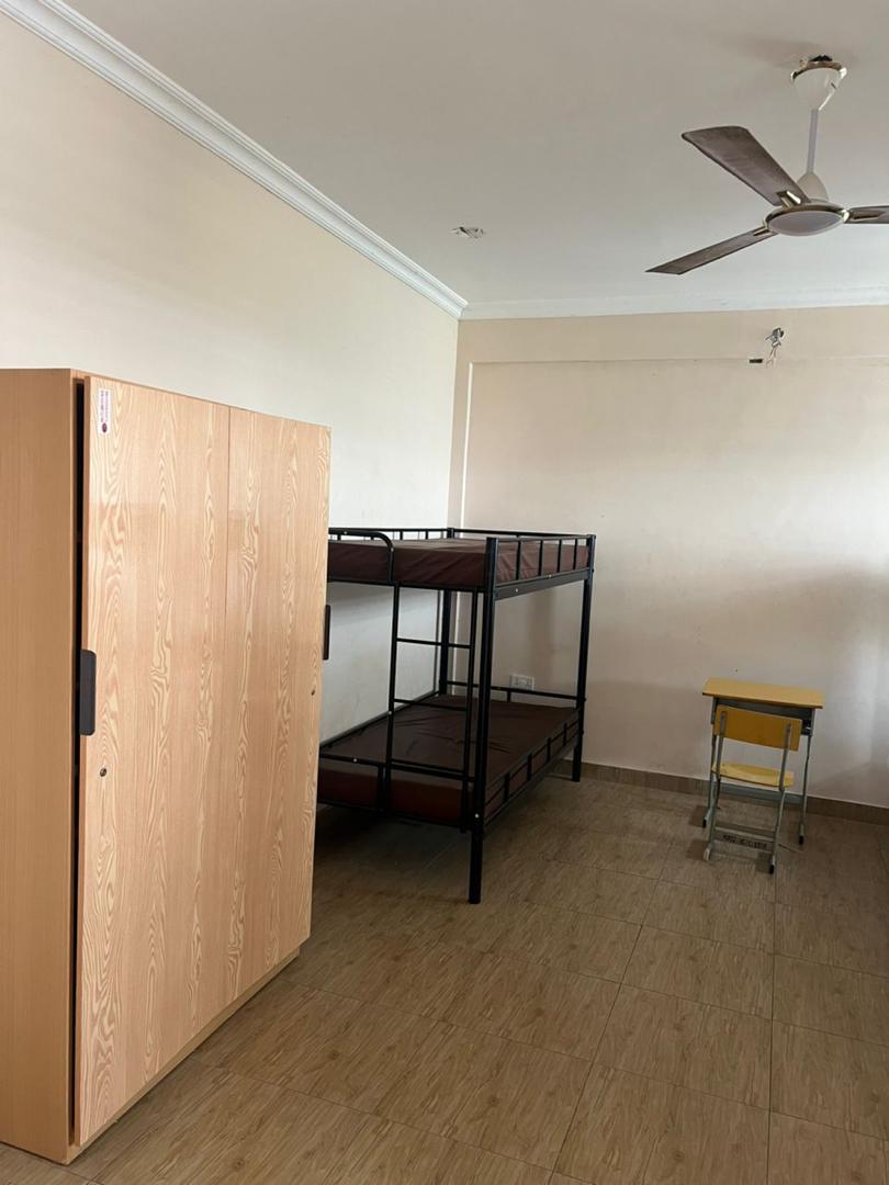 Indoor room with bunk beds, wardrobe, desk and ceiling fan